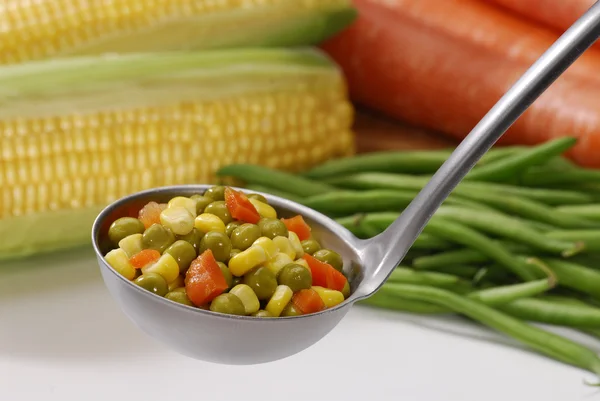 Metallic spoon with boiled fresh mixed vegetables on it. — Stock Photo, Image