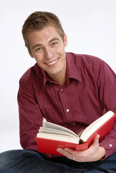 Happy young man holding and reading a book. — Stock Photo, Image