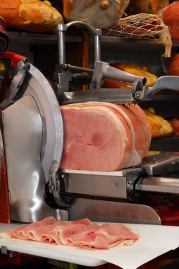 Ham slicer and prosciutto ham in a warehouse. clipart