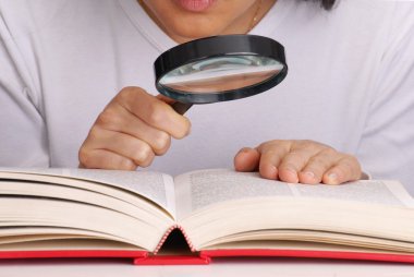 kitap okuma Büyüteç tutan genç kadın.