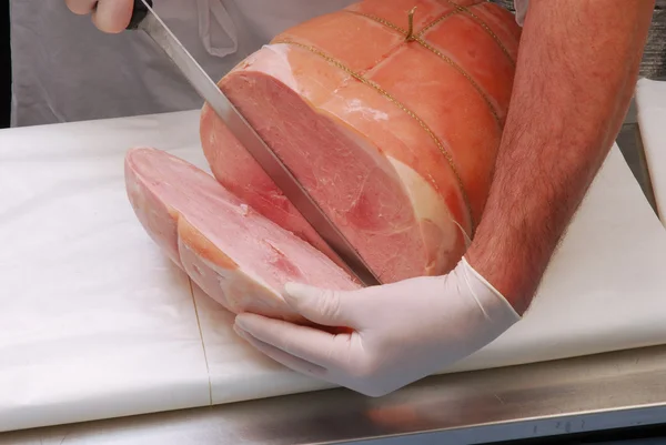 Carnicero trabajando en una porción de jamón prosciutto . — Foto de Stock