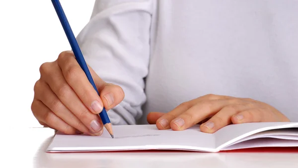 Escritura femenina en un cuaderno. Sostener un lápiz azul . — Foto de Stock