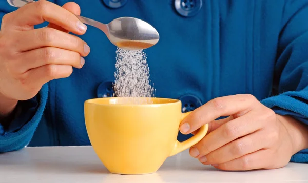 Woman pouring sugar on coffee cup. — Stock Photo, Image