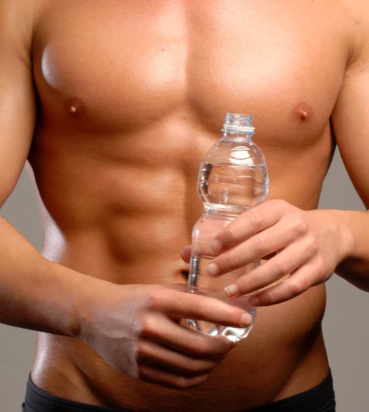 Kształt i zdrowe ciało człowiek trzyma butelkę wody mineralnej. — Zdjęcie stockowe