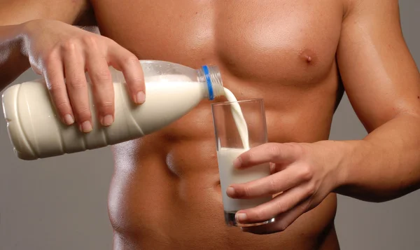 Shaped and healthy body man pouring milk glass. — Stock Photo, Image