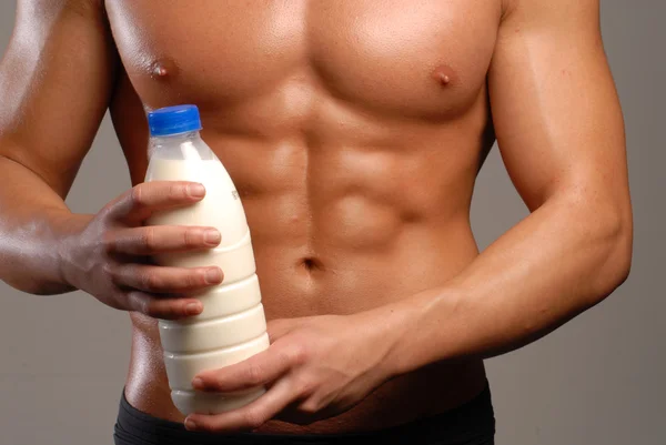 Kształt i zdrowe ciało człowiek trzyma butelkę mleka. — Zdjęcie stockowe