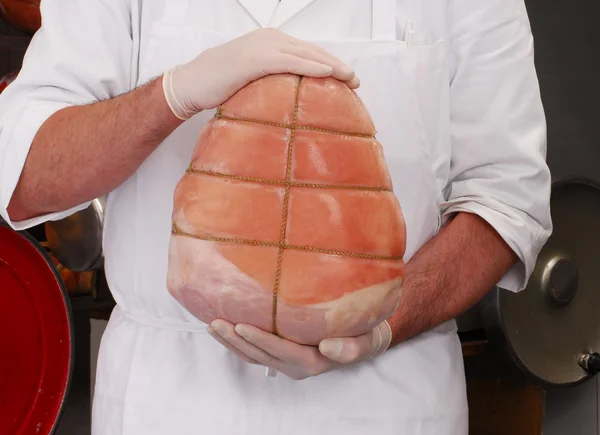 Açougueiro segurando presunto tradicional prosciutto — Fotografia de Stock