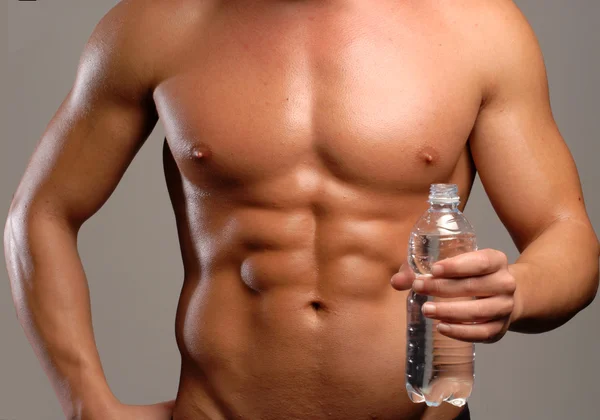 Shaped and healthy body man holding mineral water bottle. — Stock Photo, Image