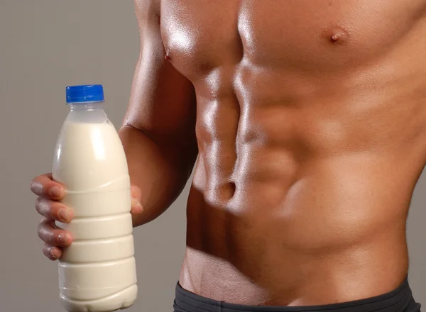 Kształt i zdrowe ciało człowiek trzyma butelkę mleka. — Zdjęcie stockowe