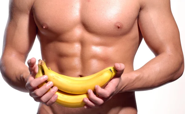 Tvarované a zdravé tělo muž, který držel čerstvých banánů — Stock fotografie