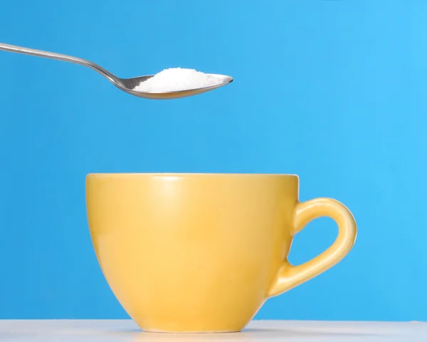 Pouring sugar on a yellow cup. — Stock Photo, Image