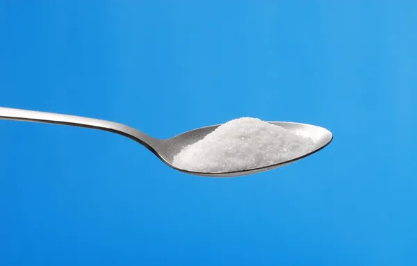 Zucker Teelöffel auf blauem Hintergrund. — Stockfoto