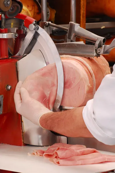 Carne de açougueiro cortando presunto prosciutto em fatiador de presunto . — Fotografia de Stock