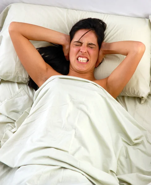 Una mujer cansada frustrada esconde su cabeza y grita porque no puede dormir — Foto de Stock