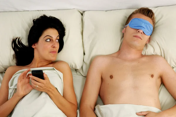 Young woman chatting on a mobile phone in bed — Stock Photo, Image