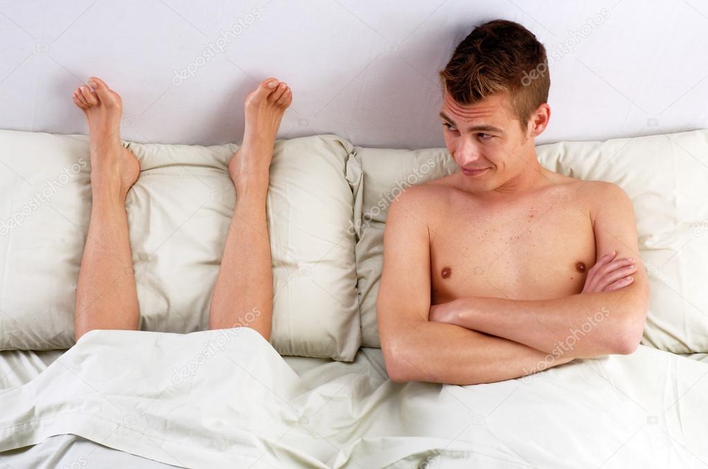 Disgust young man smelling woman feet.Funny couple lying down on bed.