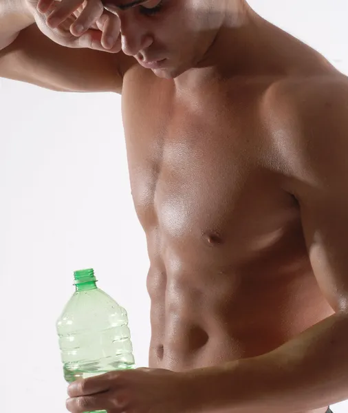 Tired muscular man holding bottle of water — Stock Photo, Image