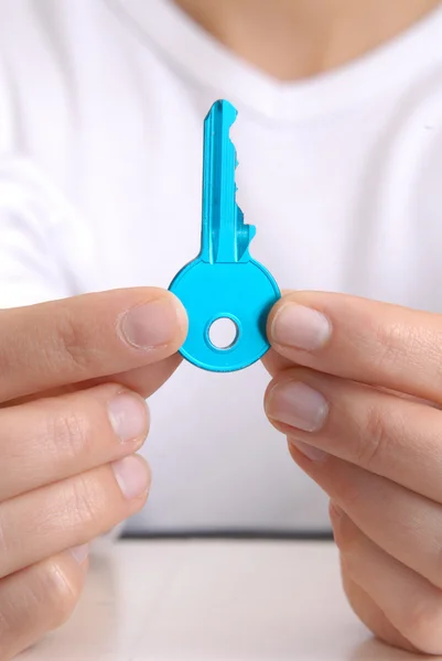 Junge Frau zeigt einen blauen Schlüssel. — Stockfoto