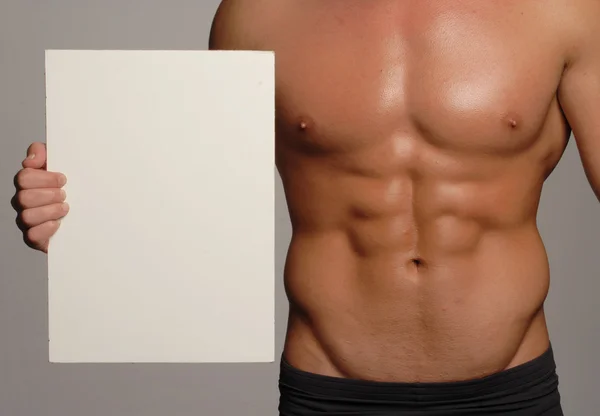 Homem de corpo em forma e saudável segurando um painel branco, em forma abdominal Imagem De Stock