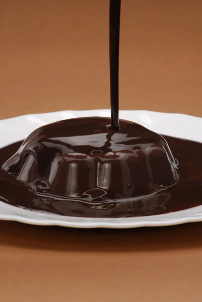 Un pudding au chocolat dans une assiette. Un flan au chocolat dans une assiette. Flux de chocolat sur le pudding . — Photo