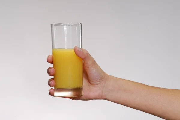 Mão feminina segurando um suco de laranja — Fotografia de Stock