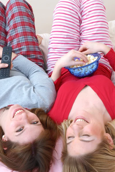 Two young women eating popcorn on bed. — Stock Photo, Image