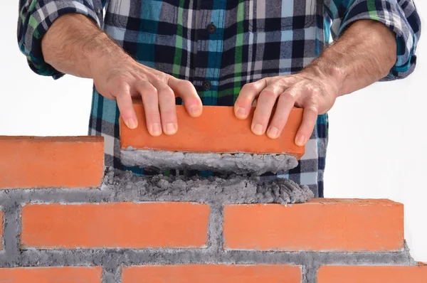 Mano del constructor sosteniendo un ladrillo y construyendo una pared . — Foto de Stock