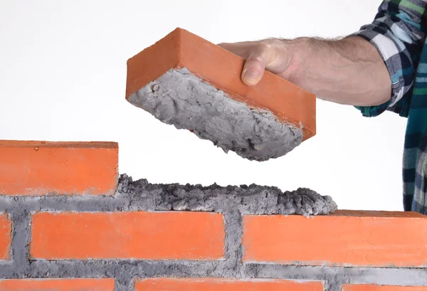 Κατασκευαστή χέρι κρατώντας ένα τούβλο και να κατασκευάζει ένα τείχος. — Φωτογραφία Αρχείου