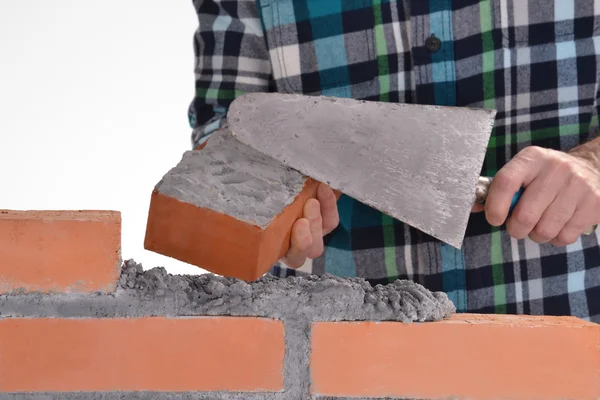 Costruttore mano che tiene un mattone e la costruzione di un muro . — Foto Stock