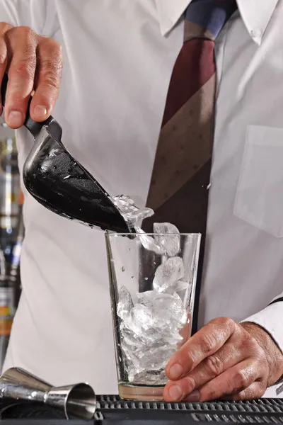 Barman gieten ijsblokjes op cocktailglas — Stockfoto