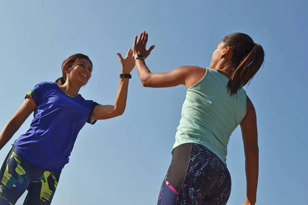 2人の若いフィットネススポーツラテン女性が青い屋外の空を背景に握手 — ストック写真