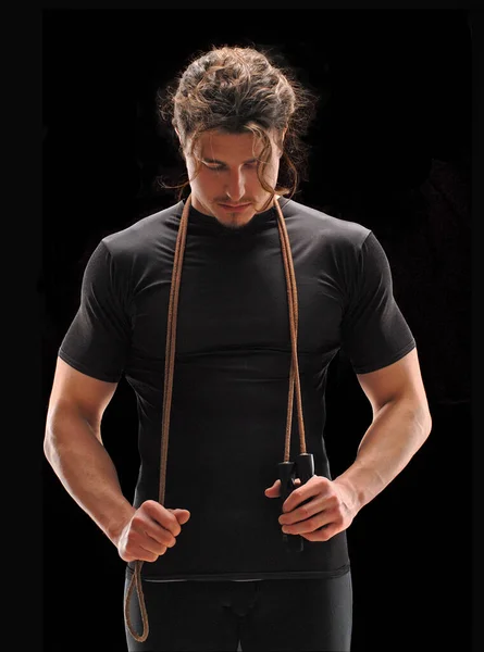若いですフィットネス男保持ジャンプスポーツロープ上の黒の背景 — ストック写真