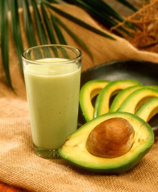 Kırsal arka planda doğal avokado suyu ve dilimlenmiş avokado malzemeleri..