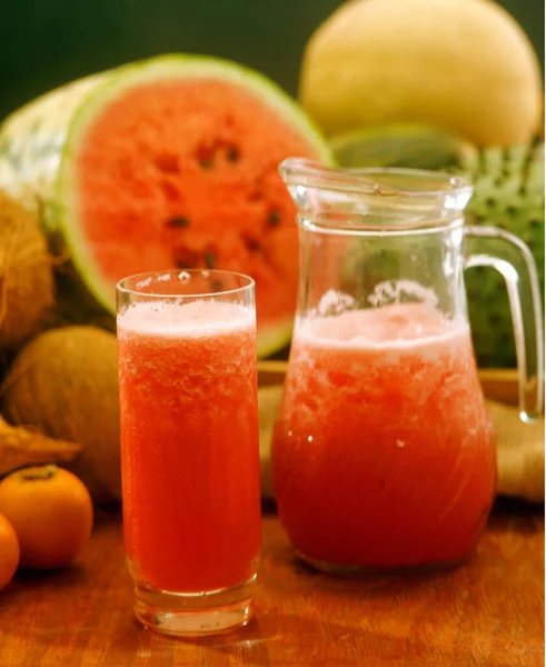 热带水果背景下的新鲜西瓜果汁杯和玻璃瓶 — 图库照片