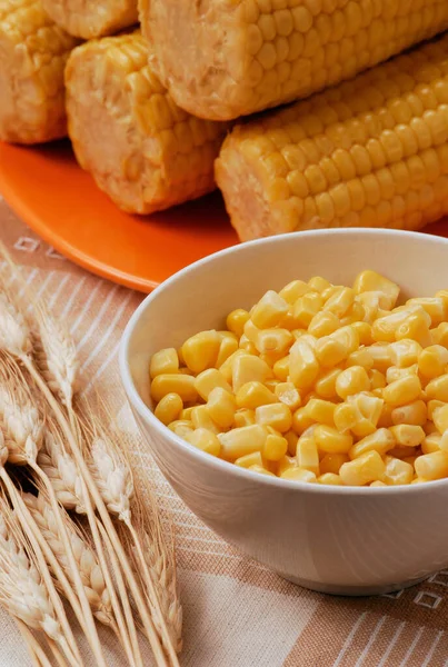 bowl of fresh sweet corn and ears of wheat and corn background