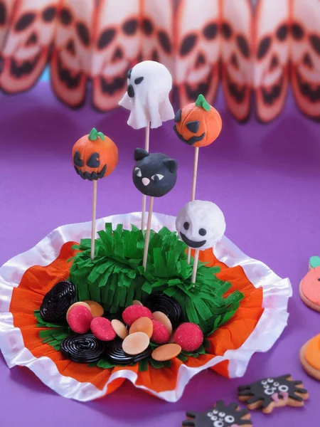 Halloween party lollipops on skulls pink background.