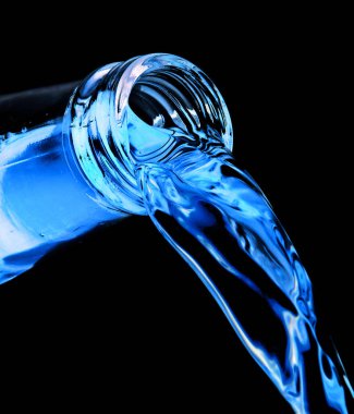 Bottle pouring blue neon drink on black background.