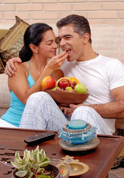 快乐的年轻夫妇在客厅里吃热带水果 — 图库照片