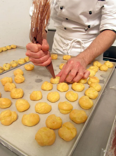 Pastry chef preparing and making chocolate sweets using cream pastry bag