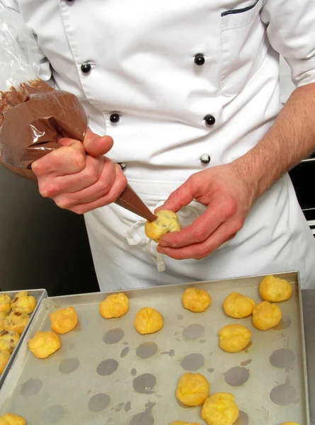 Pastry chef preparing and making chocolate sweets using cream pastry bag