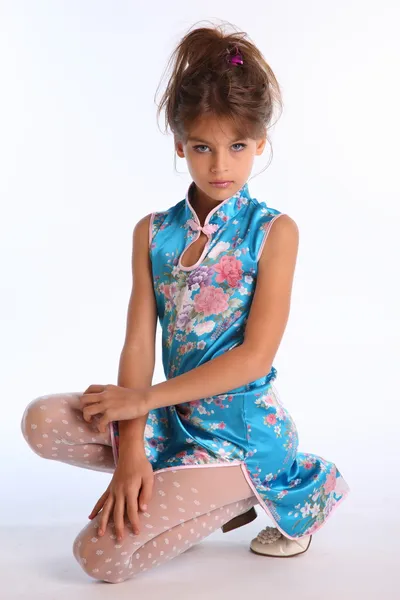 Malá dívka pózuje v ateliéru v modrých šatech — Stock fotografie
