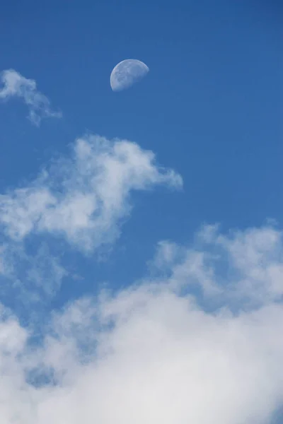 moon and clouds against blue sky