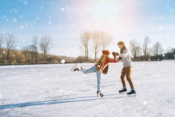 Pareja cariñosa en suéteres cálidos divirtiéndose en hielo. Mujer y hombre patinando sobre hielo al aire libre en un día soleado y nevado. Fecha activa en la arena de hielo en invierno Nochebuena. Actividades románticas y concepto de estilo de vida. Imagen De Stock