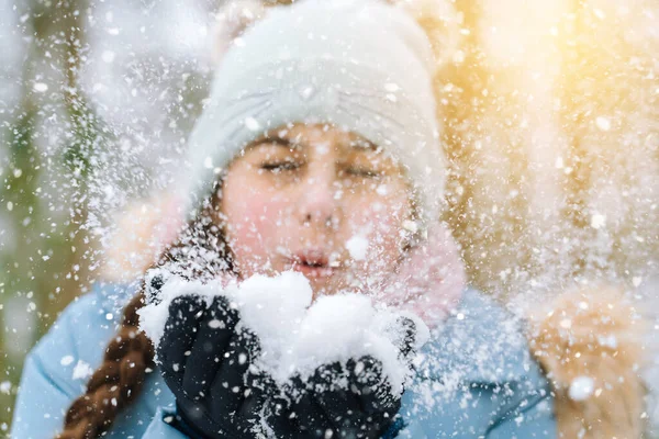 Fille jouant sur la neige en hiver. Joyeux enfants dans la belle forêt enneigée d'hiver le jour de Noël. fille souffle neige sur flocons de neige fond bokeh. — Photo