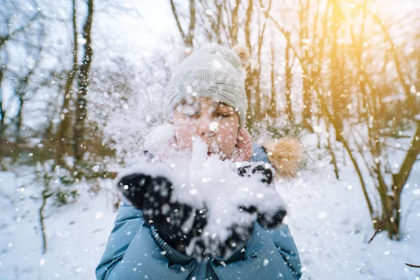 Fille jouant sur la neige en hiver. Joyeux enfants dans la belle forêt enneigée d'hiver le jour de Noël. fille souffle neige sur flocons de neige fond bokeh. — Photo