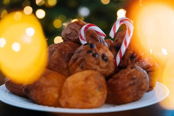 Oliebollen, tradicional pastelería holandesa para Nochevieja con destellos. albóndigas de aceite o buñuelos con azúcar en polvo encima. Árbol de Navidad luces bokeh en el fondo. Alimentos típicos. Imagen De Stock