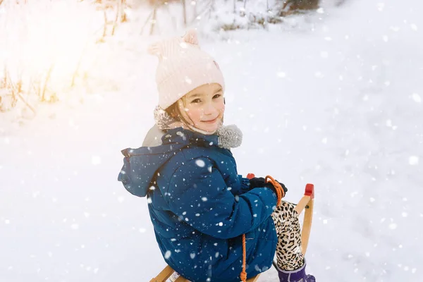 Deux enfants montent sur luge rétro en bois le jour ensoleillé de l'hiver. Jeux actifs d'hiver en plein air. Activités hivernales pour les enfants. Enfants jouant avec la neige dans le parc. — Photo