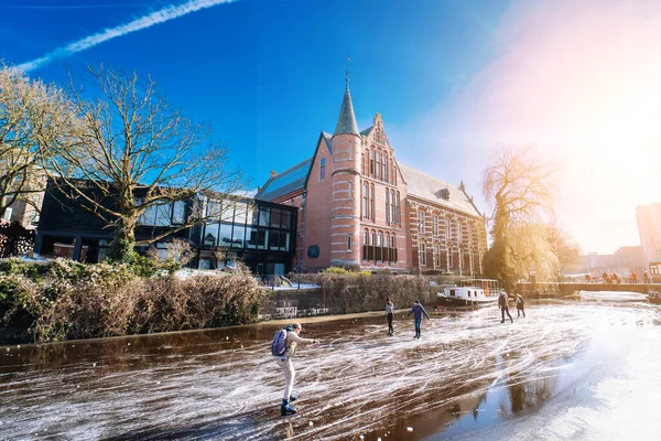 Gente patinando en el canal congelado en el centro de la ciudad en Holanda. Pueblos haciendo fotos, caminando y patinando en el canal congelado en invierno. Diversión de invierno en la ciudadGroninga. Países Bajos. 14.02.2021. — Foto de Stock