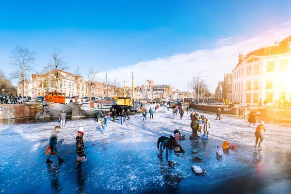 People ice scating on frozen canal in city center in Netherlands. Peoples making pictures, walking and skating on frozen canal in winter. Winter fun in cityGroningen. Netherlands. 14.02.2021. — Stock Photo, Image