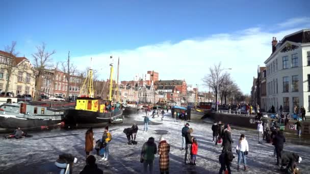 Människor skridskoåkning på frusen kanal i centrum av Nederländerna. Folk gör bilder, går och åker skridskor på frusen kanal på vintern. Vinternöje i stadenGroningen. Nederländerna. 14.02.2021. — Stockvideo